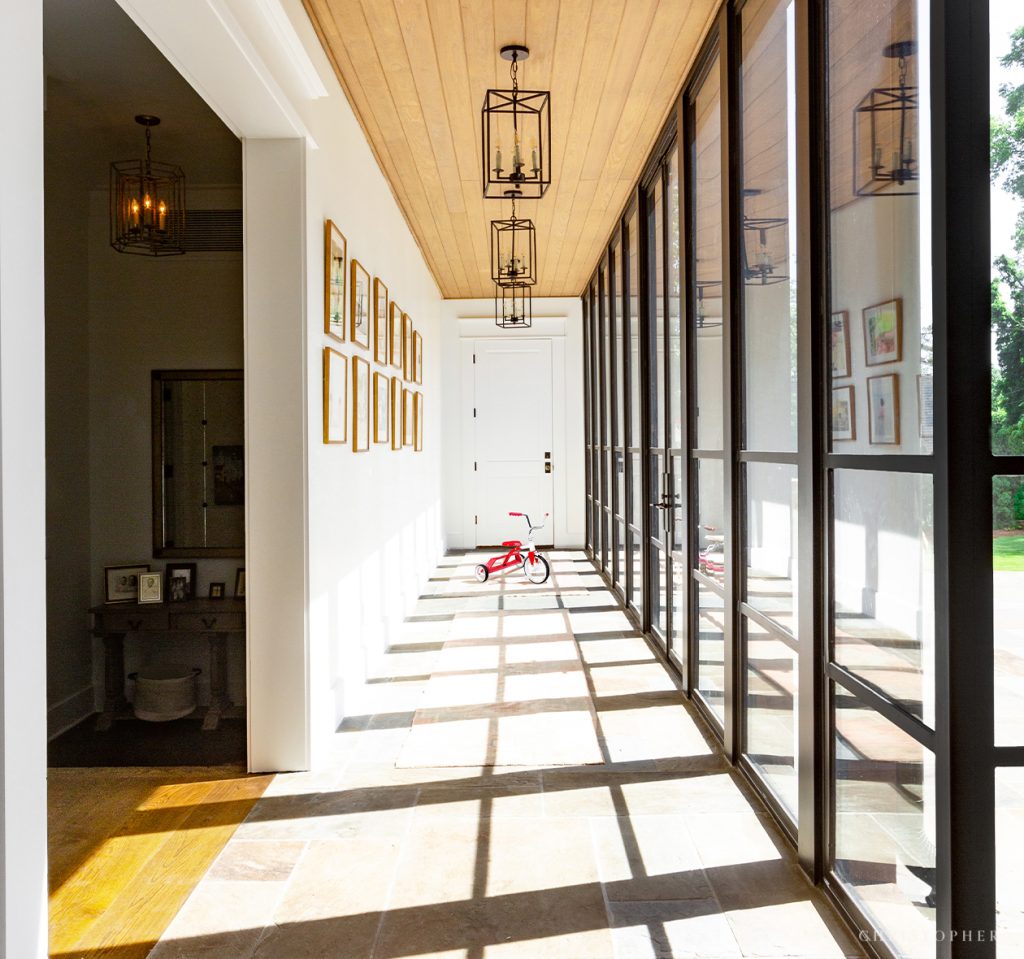 Christopher Architecture and Interiors Showhouse Hallway with Floor to Ceiling Glass Windows and Pecky Cypress Ceilings